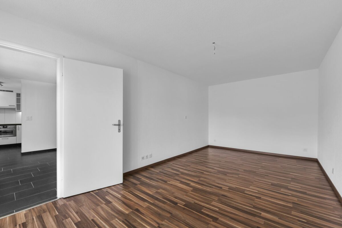 Leeres Wohn- oder Schlafzimmer mit offener Tür zur Küche