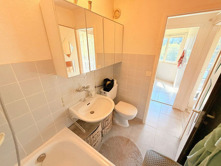 Helles Badezimmer mit Badewanne und Spiegelschrank