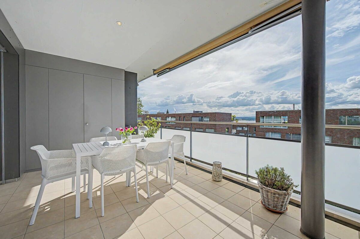 Große überdachte Balkonterrasse mit Esstisch und Ausblick
