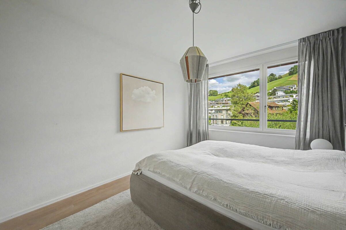 Helles Schlafzimmer mit großem Fenster und Aussicht ins Grüne