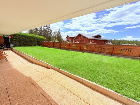 Überdachte Terrasse mit Rasen und Holzzaun