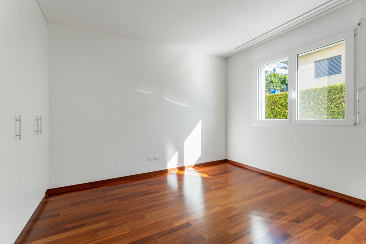 Leerer, heller Raum mit Holzfußboden und Fenster