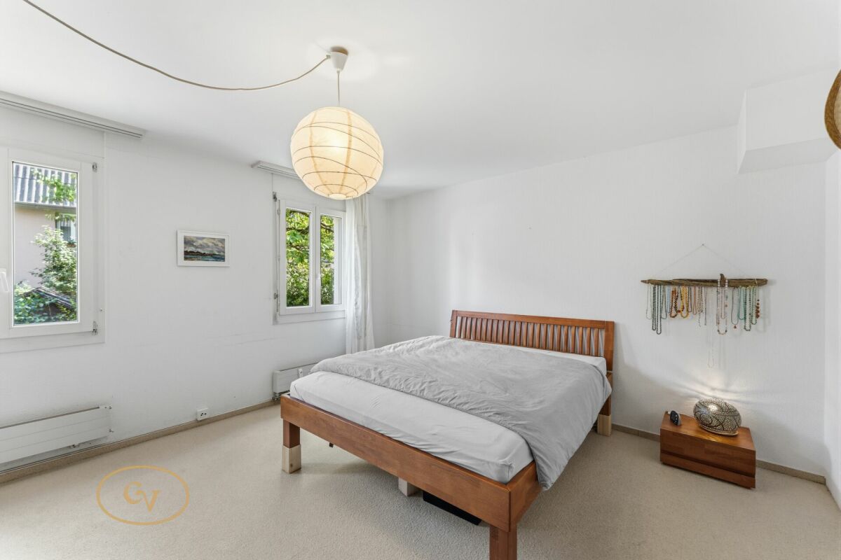 Helles Schlafzimmer mit Holzbett und zwei Fenstern