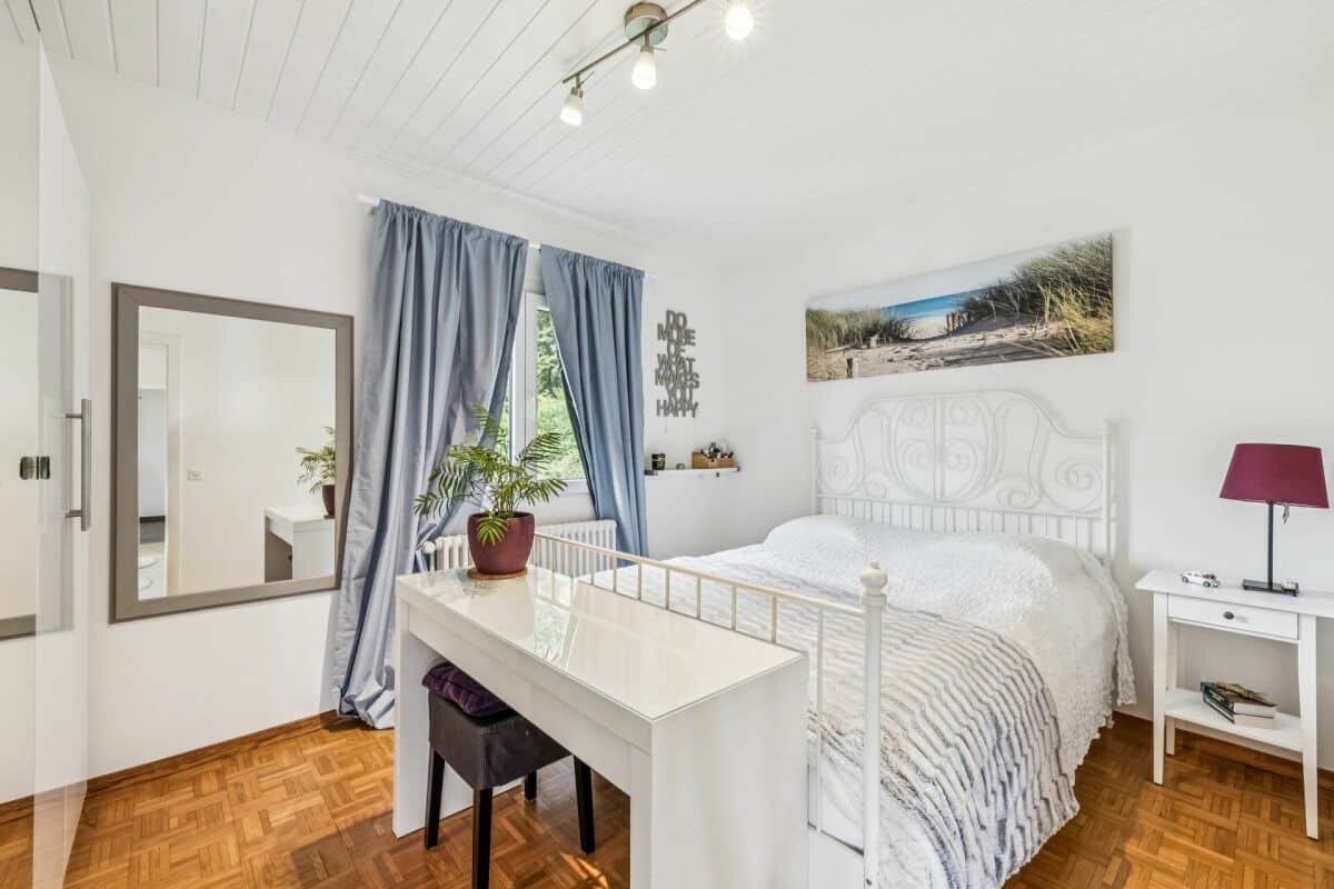 Helles Schlafzimmer mit weißem Bett und Parquetboden