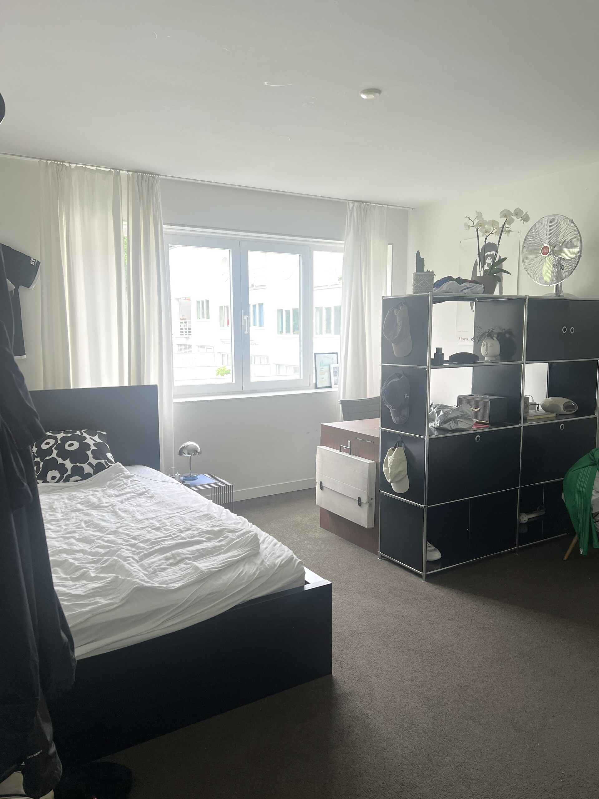 Helles Schlafzimmer mit weißem Fenster und schwarzem Bettgestell