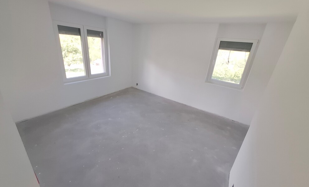 Leerer, frisch renovierter Raum mit zwei Fenstern