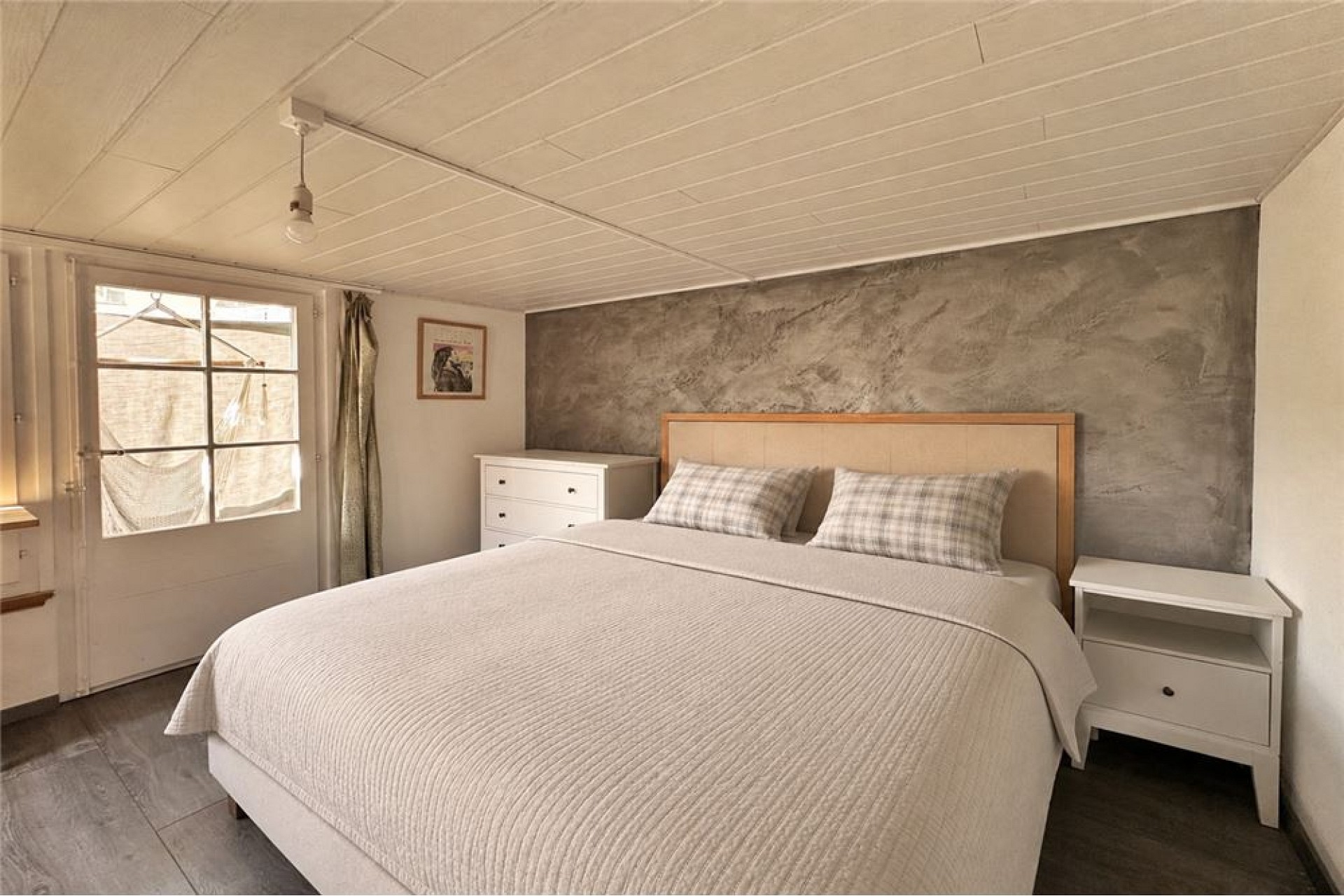 Schlafzimmer mit schlichtem Bett und rustikal-modernen Akzenten