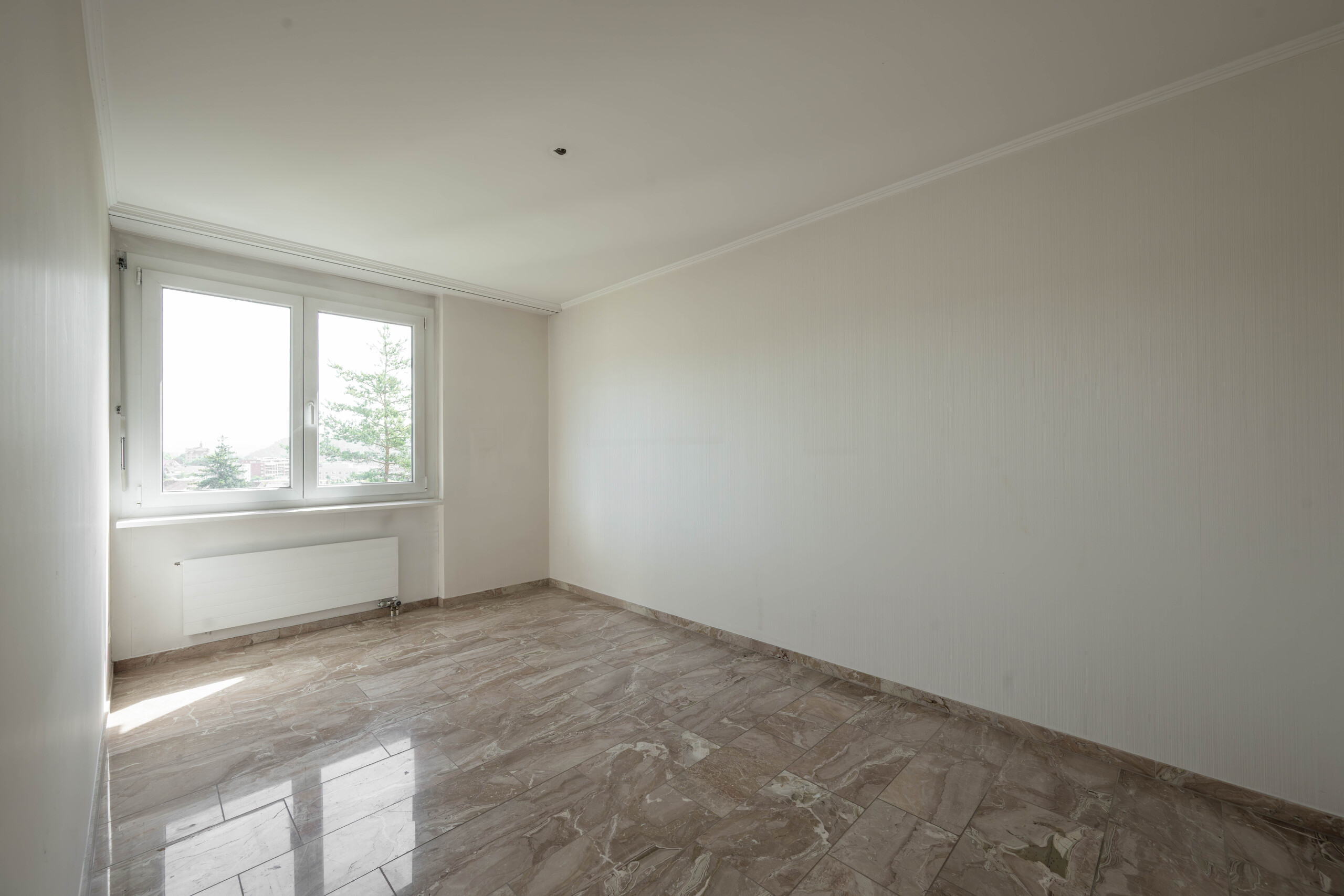 Leerer heller Raum mit Fliesenboden und Fenster