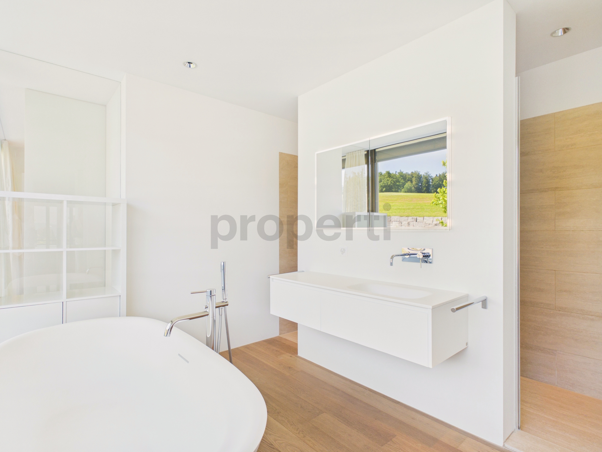 Modernes Badezimmer mit freistehender Wanne und Blick ins Grüne