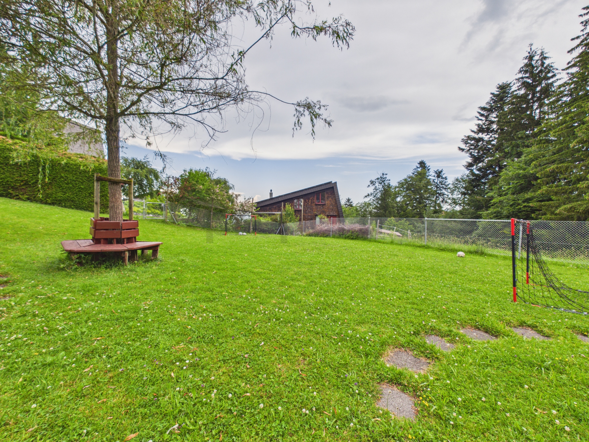 Großer eingezäunter Garten mit Holzsitzbank und Spieltoren