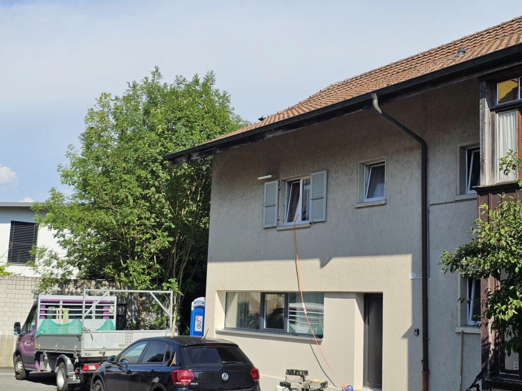 Außenansicht eines Wohnhauses mit parkendem Auto im Vordergrund