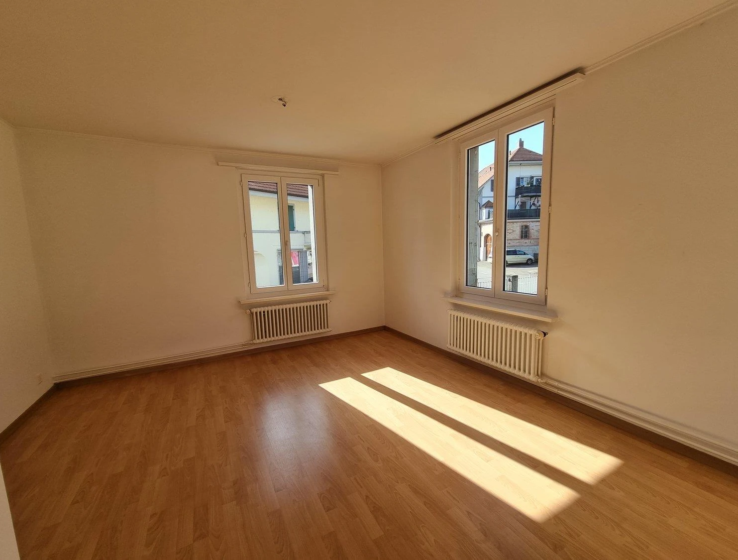 Leerer, sonnendurchfluteter Raum mit Parkettboden