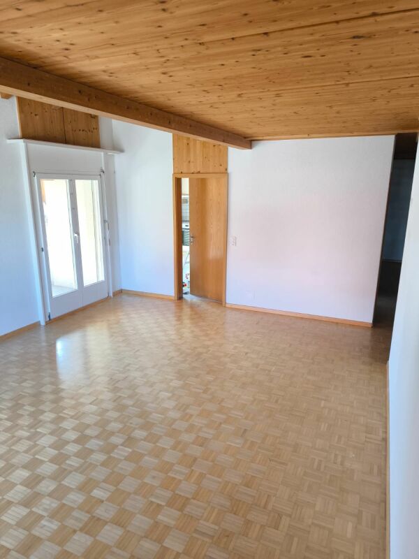 Leerer Wohnraum mit Holzdecke und Parkettboden