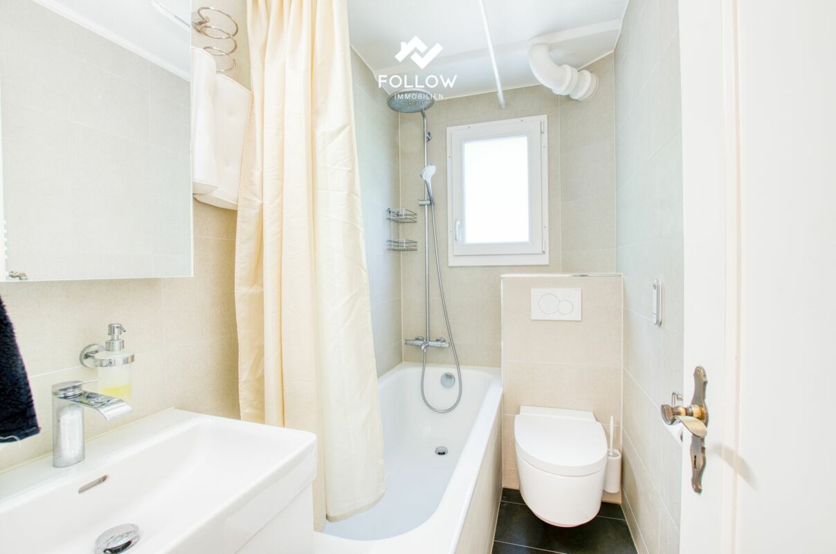 Kleines helles Badezimmer mit Badewanne und WC