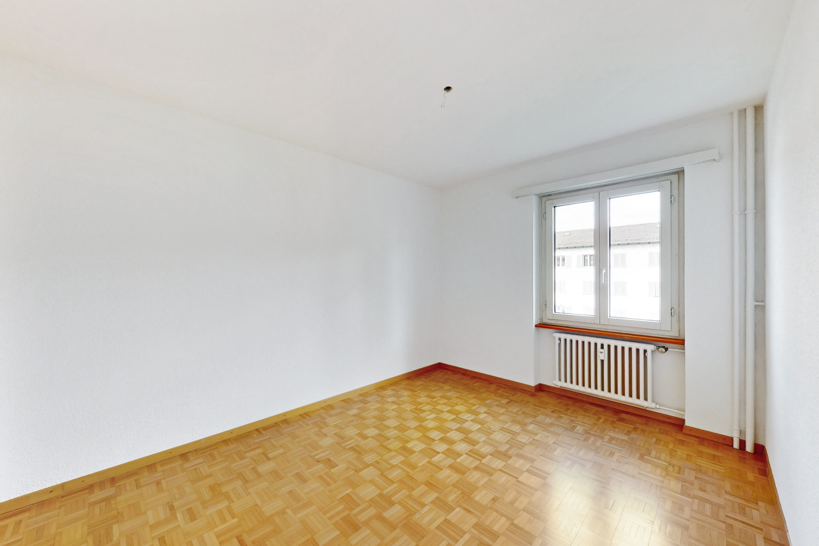 Leerer, heller Raum mit Parkettboden