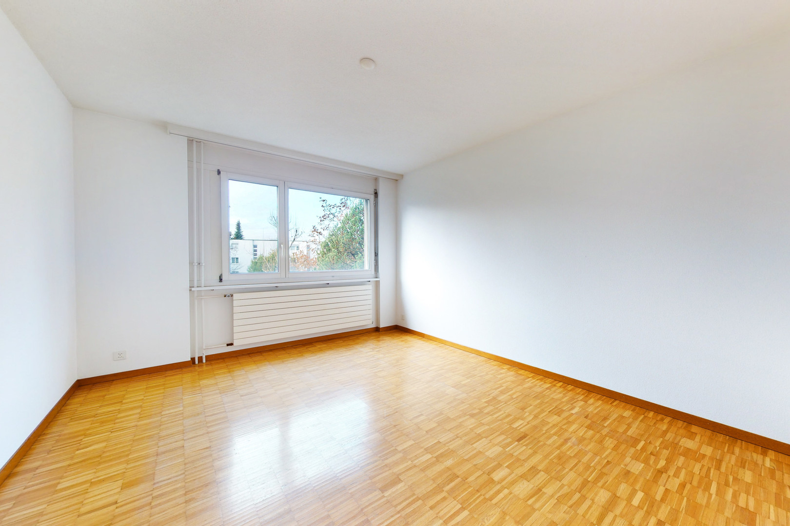 Heller leerer Wohnraum mit Parkett und Fenster