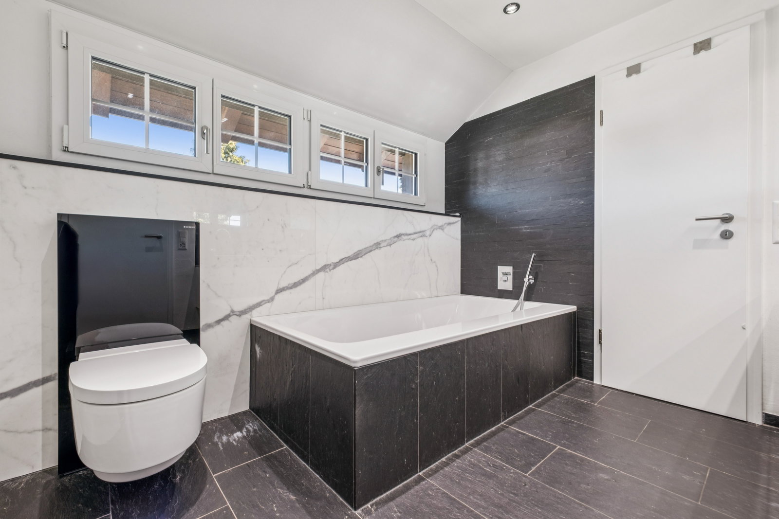 Modernes Bad mit Wanne, WC und dunkler Akzentwand
