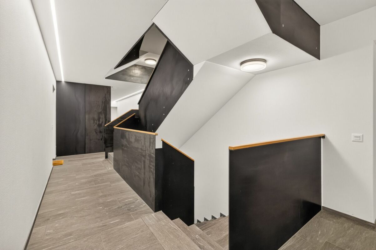 Treppenhaus mit moderner, dunkler Geländerverkleidung