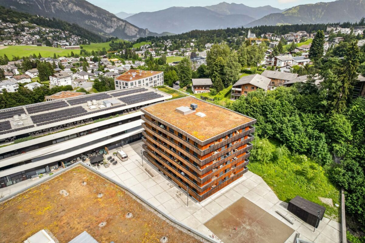 Luftaufnahme eines Wohn- und Gebäudekomplexes in alpiner Umgebung
