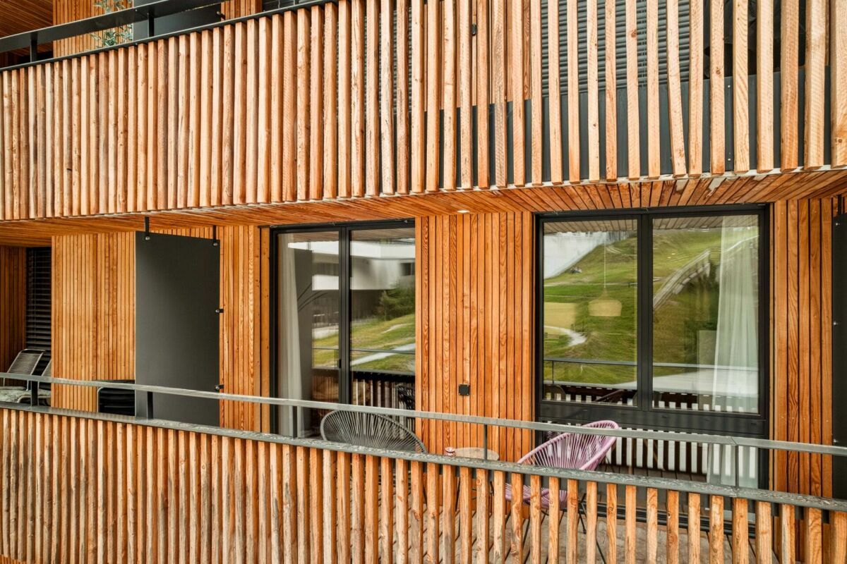 Holzverkleidete Balkonfassade mit großen Fenstern