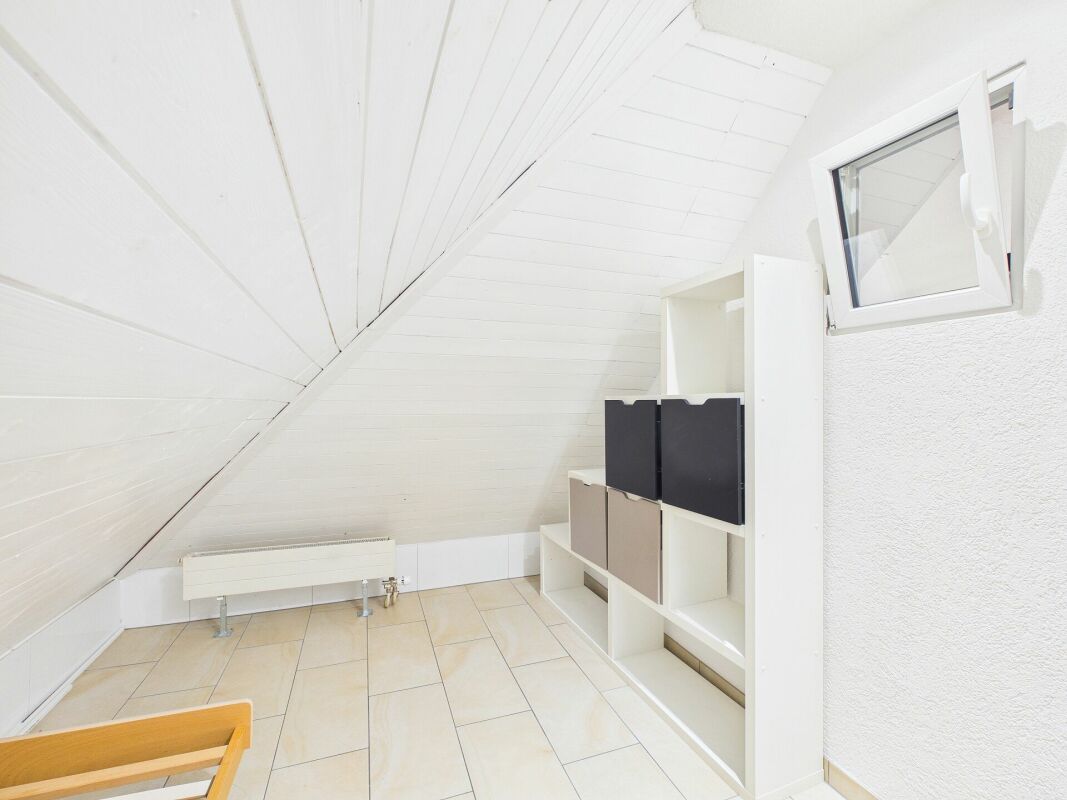 Dachgeschossraum mit weißer Wandverkleidung und Dachfenster