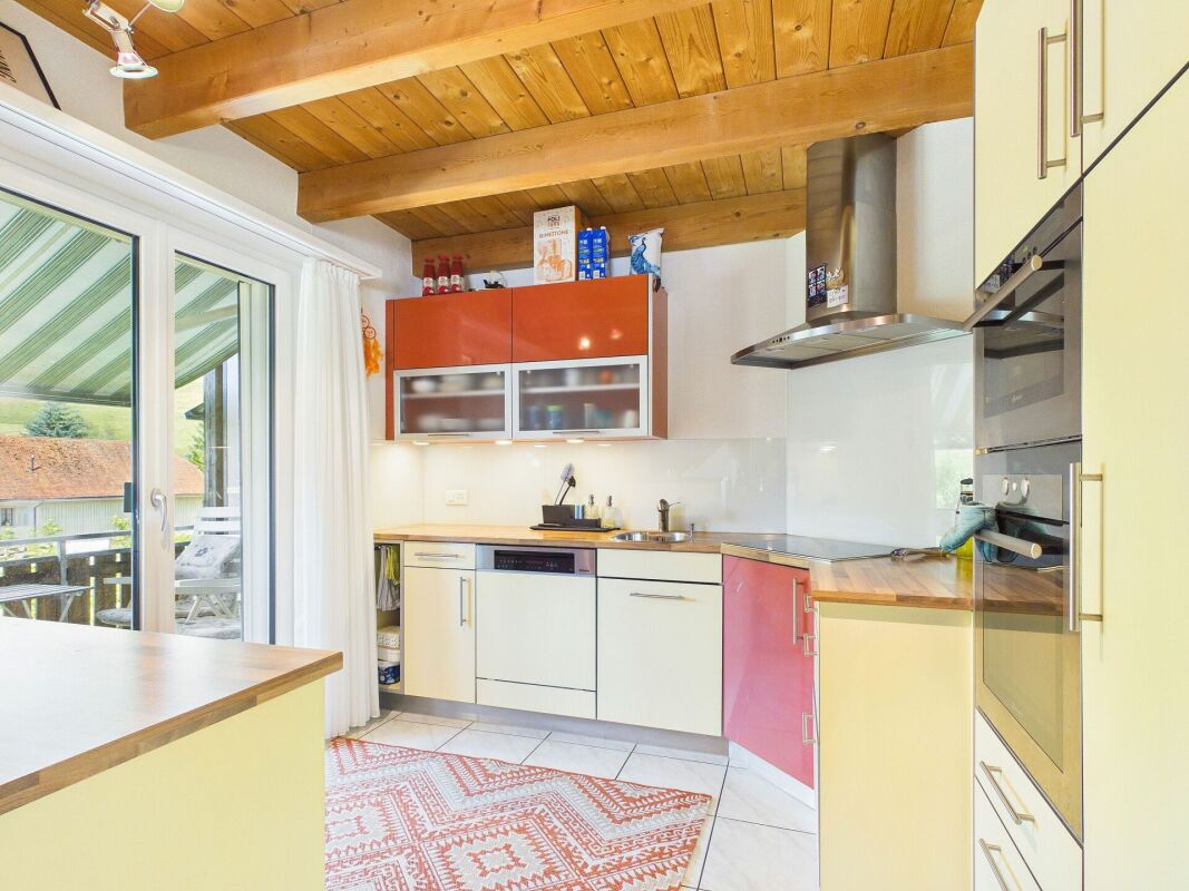 Helle Einbauküche mit Holzdecke und Zugang zum Balkon