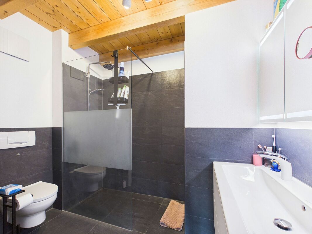 Modernes Badezimmer mit Holzdecke und dunkler Dusche