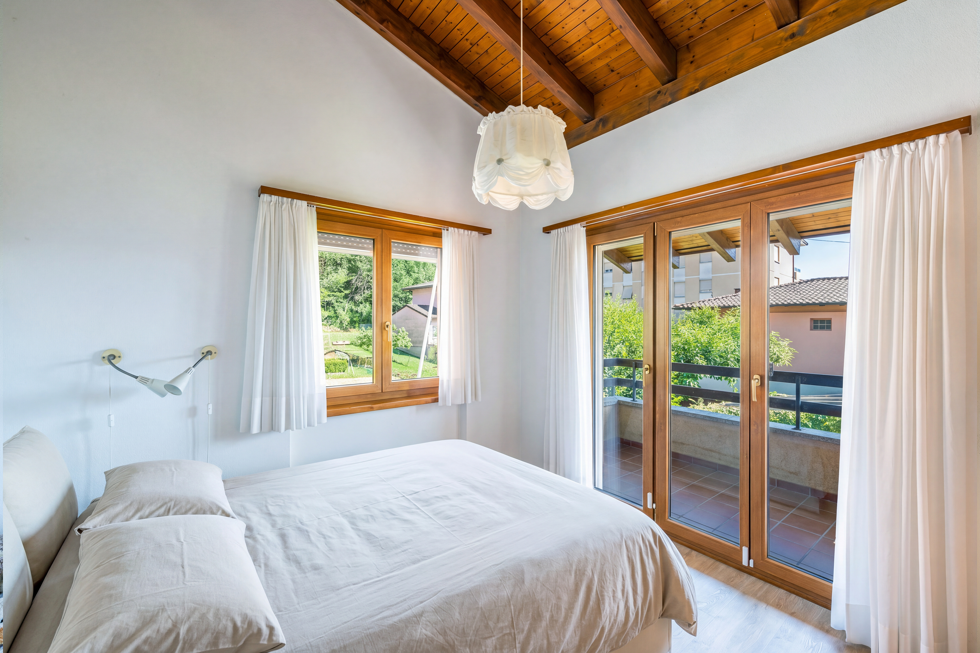 Helles Schlafzimmer mit Holzbalkendecke und Balkonzugang