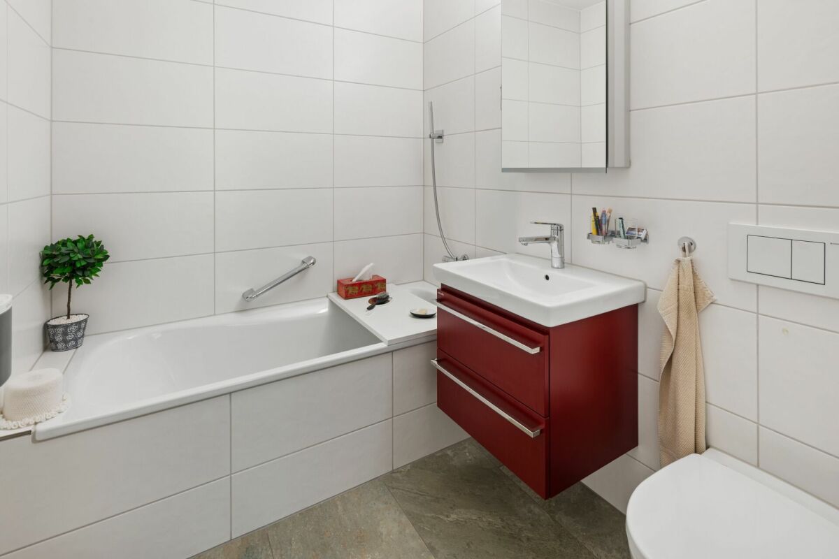 Modernes Badezimmer mit Wanne und rotem Waschtischunterschrank