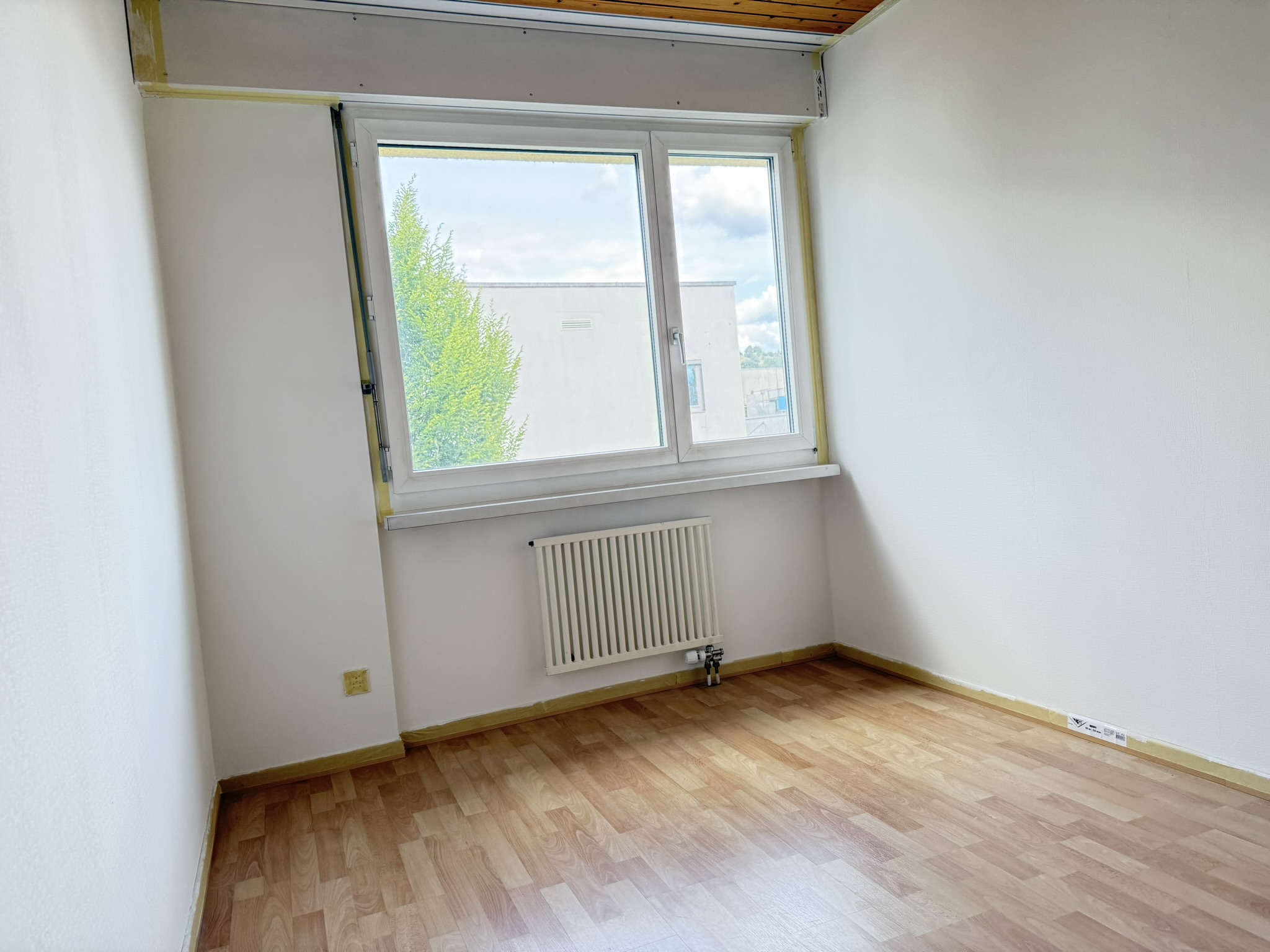 Leerer heller Raum mit Fenster und Heizung