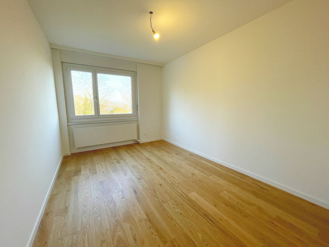 Leerer, heller Raum mit Holzparkett und Fenster
