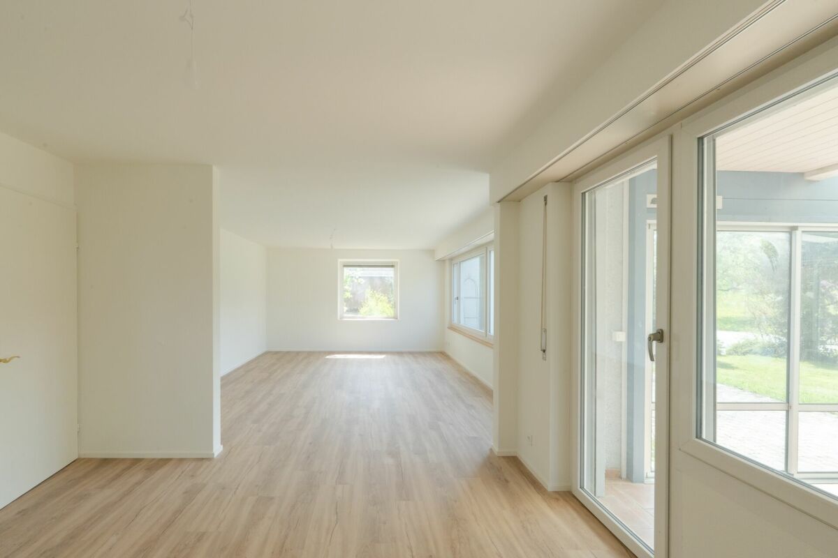 Heller leerer Innenraum mit großen Fenstern und Holzboden