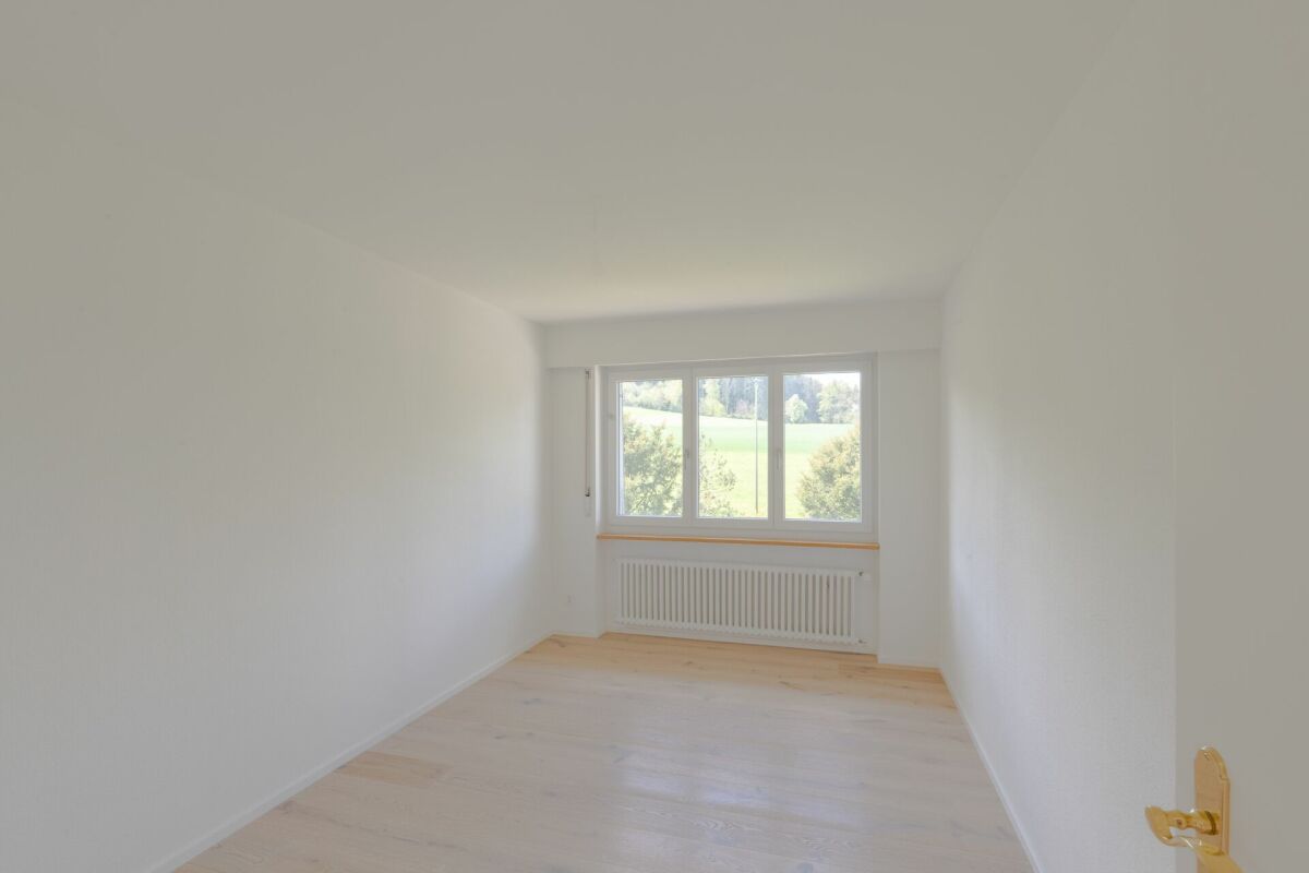 Helles, leeres Zimmer mit Fensterblick ins Grüne