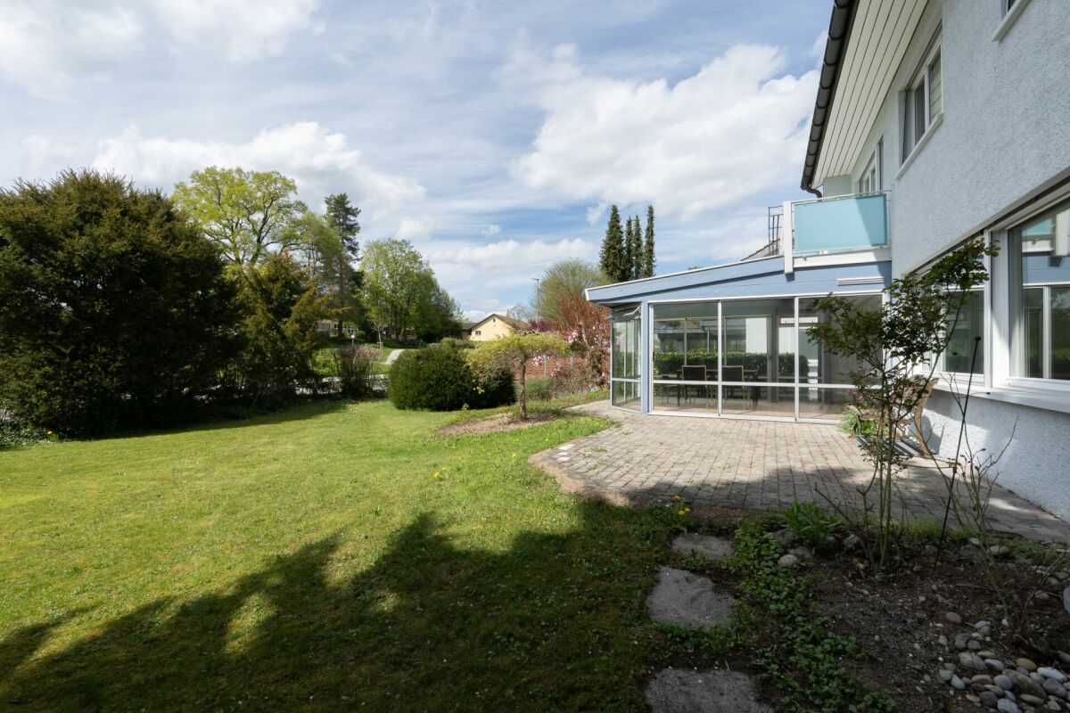 Gartenansicht eines Einfamilienhauses mit Wintergarten
