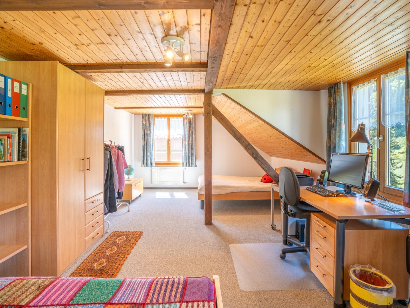 Ausgebautes Dachzimmer mit Arbeits- und Schlafbereich