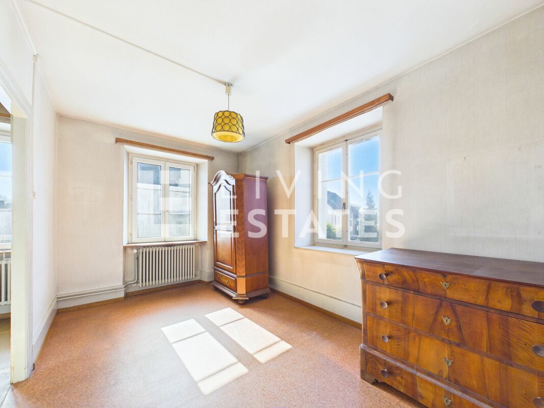 Helles Zimmer mit zwei Fenstern und antiken Holzmöbeln