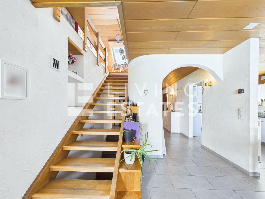 Heller Eingangsbereich mit Holztreppe und Rundbogen
