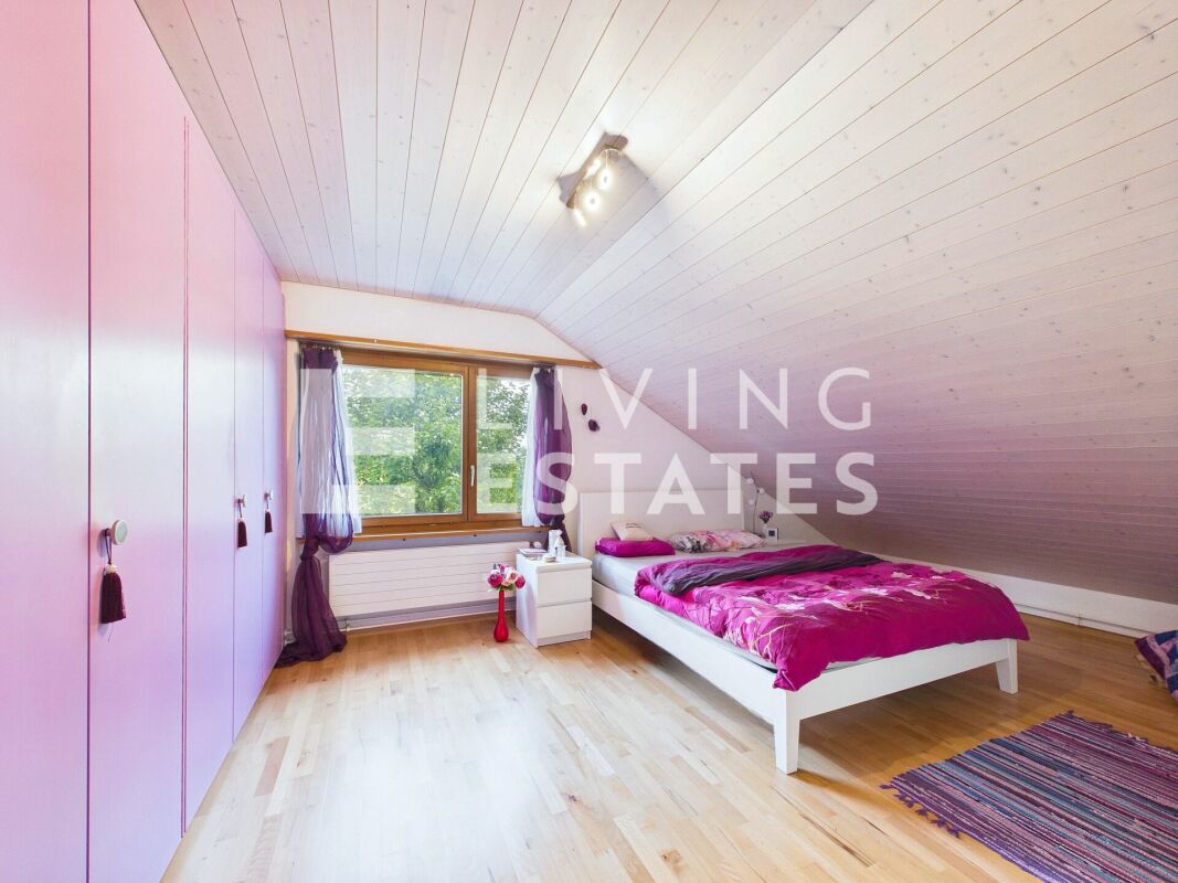 Dachgeschoss-Schlafzimmer mit großem Fenster und Einbauschrank