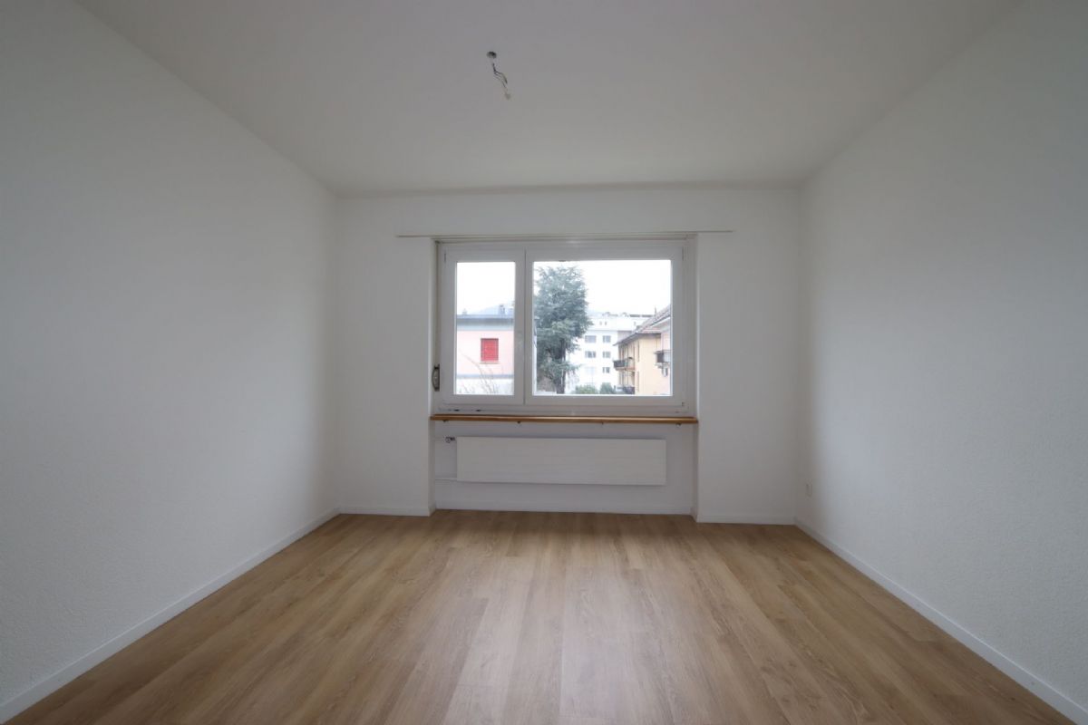 Leerer, frisch renovierter Raum mit Fenster und Holzoptikboden