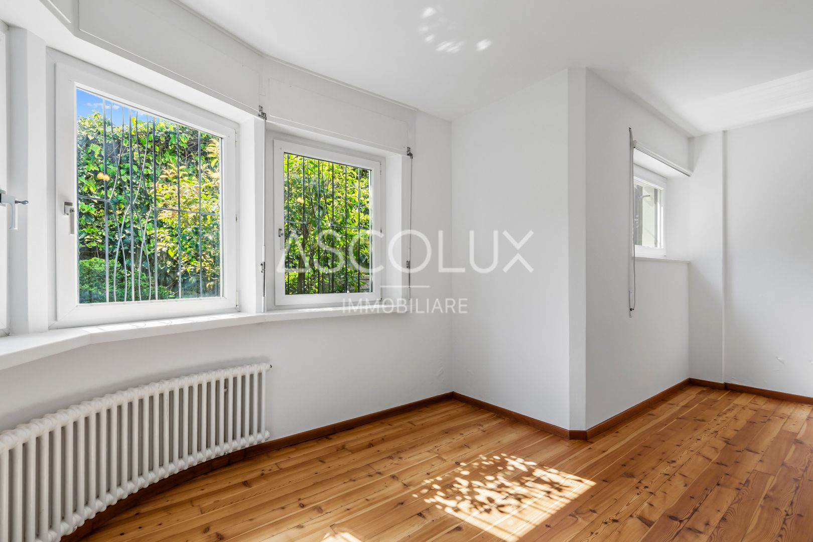 Heller leerer Raum mit Holzfußboden und Fenstern