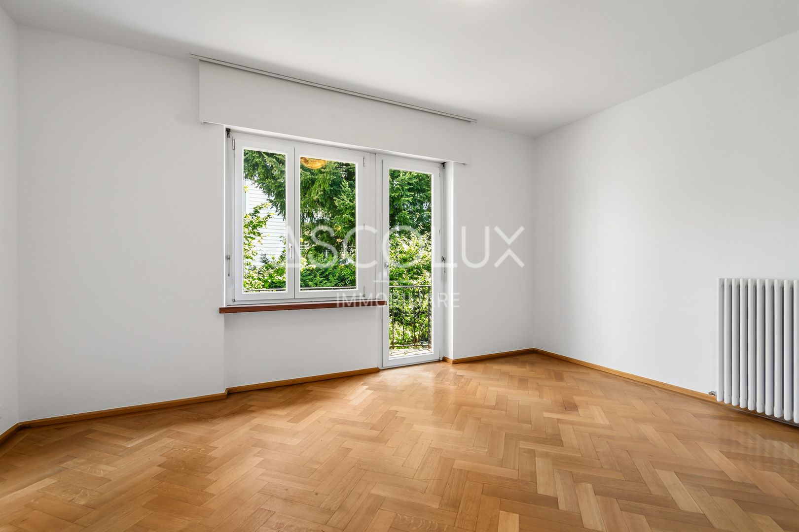 Heller leerer Wohnraum mit Parkett und Balkonblick