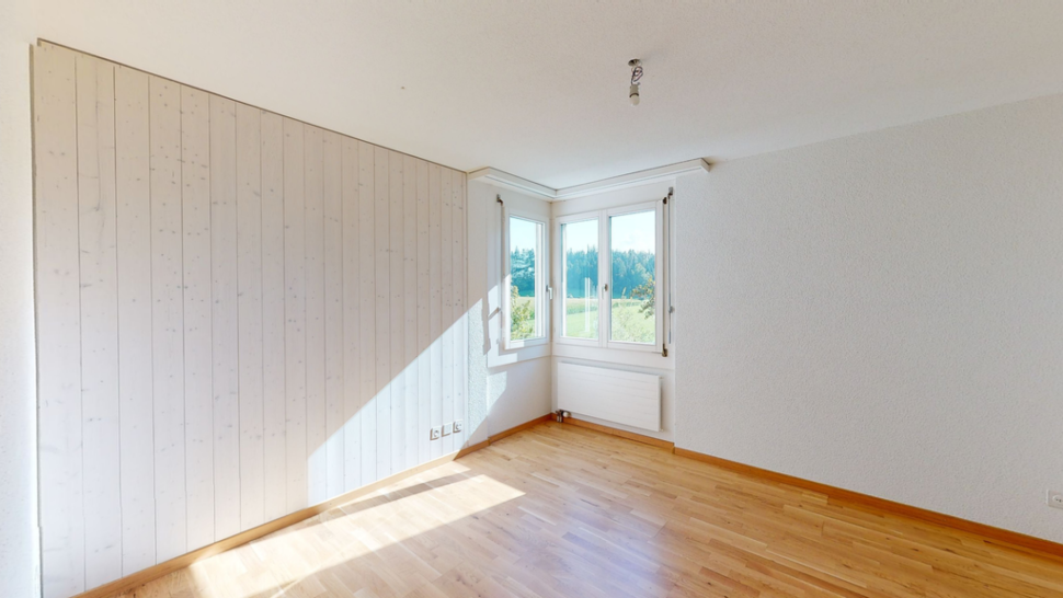 Helles leeres Schlafzimmer mit Eckfenster und Holzfußboden
