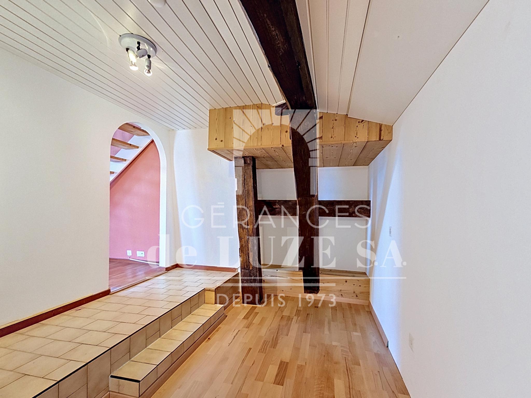 Ausgebauter Dachraum mit Holztreppe und sichtbaren Balken