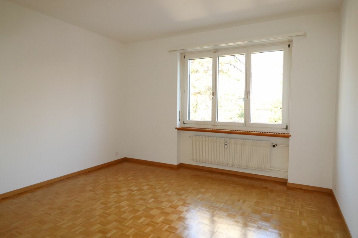 Leerer Wohnraum mit Parkett und Fenster