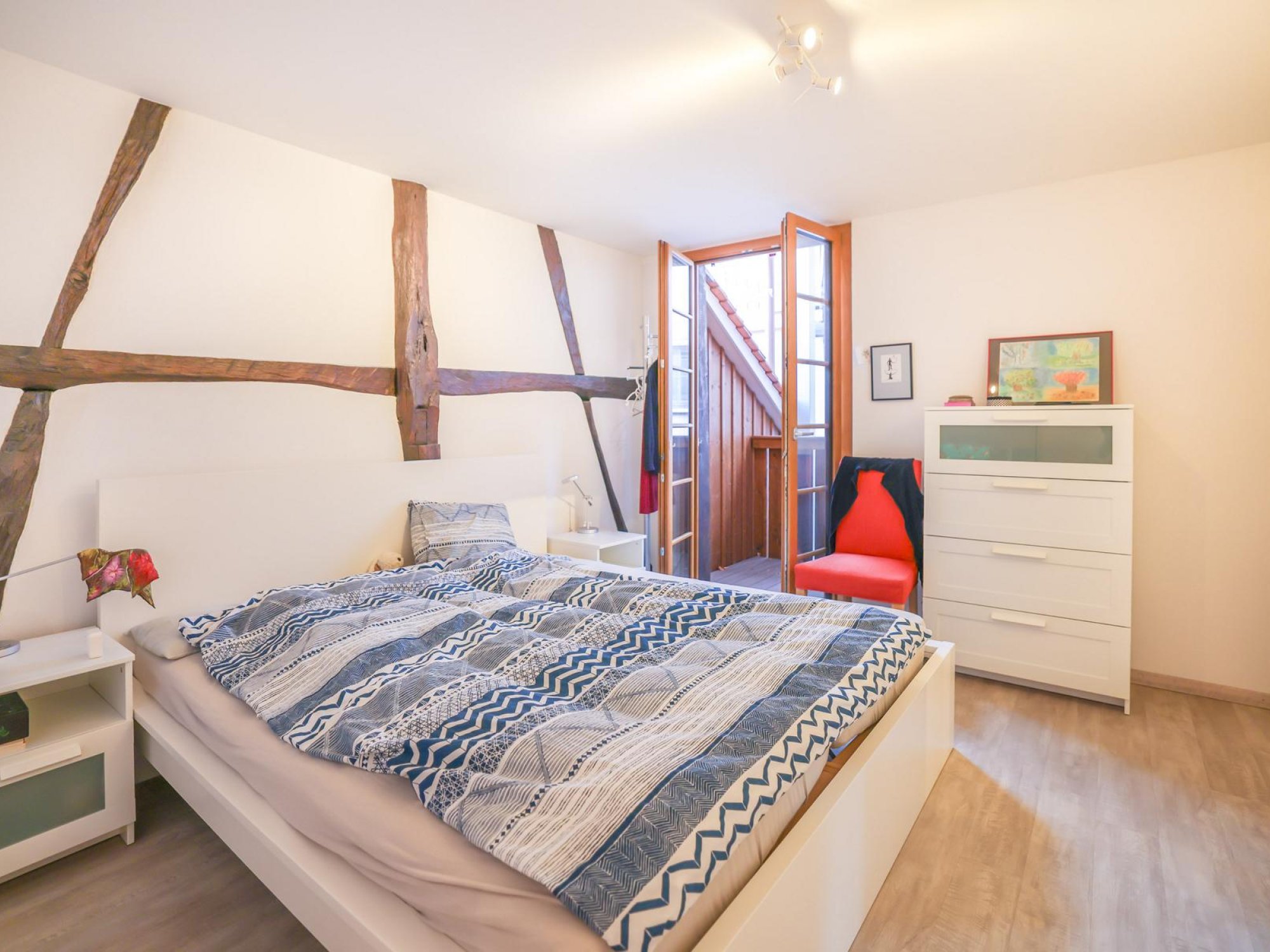 Helles Schlafzimmer mit rustikalen Holzbalken und Balkonzugang