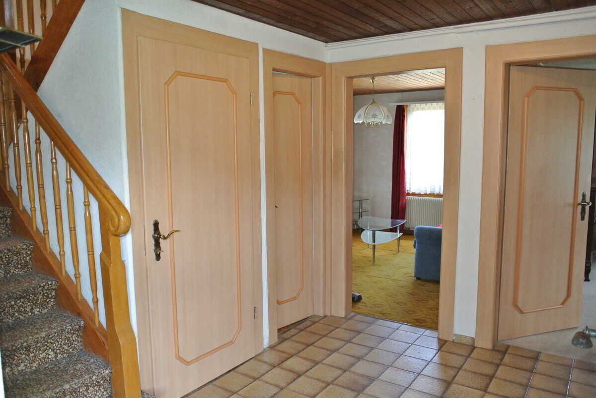 Flur mit Treppenaufgang und mehreren Innentüren