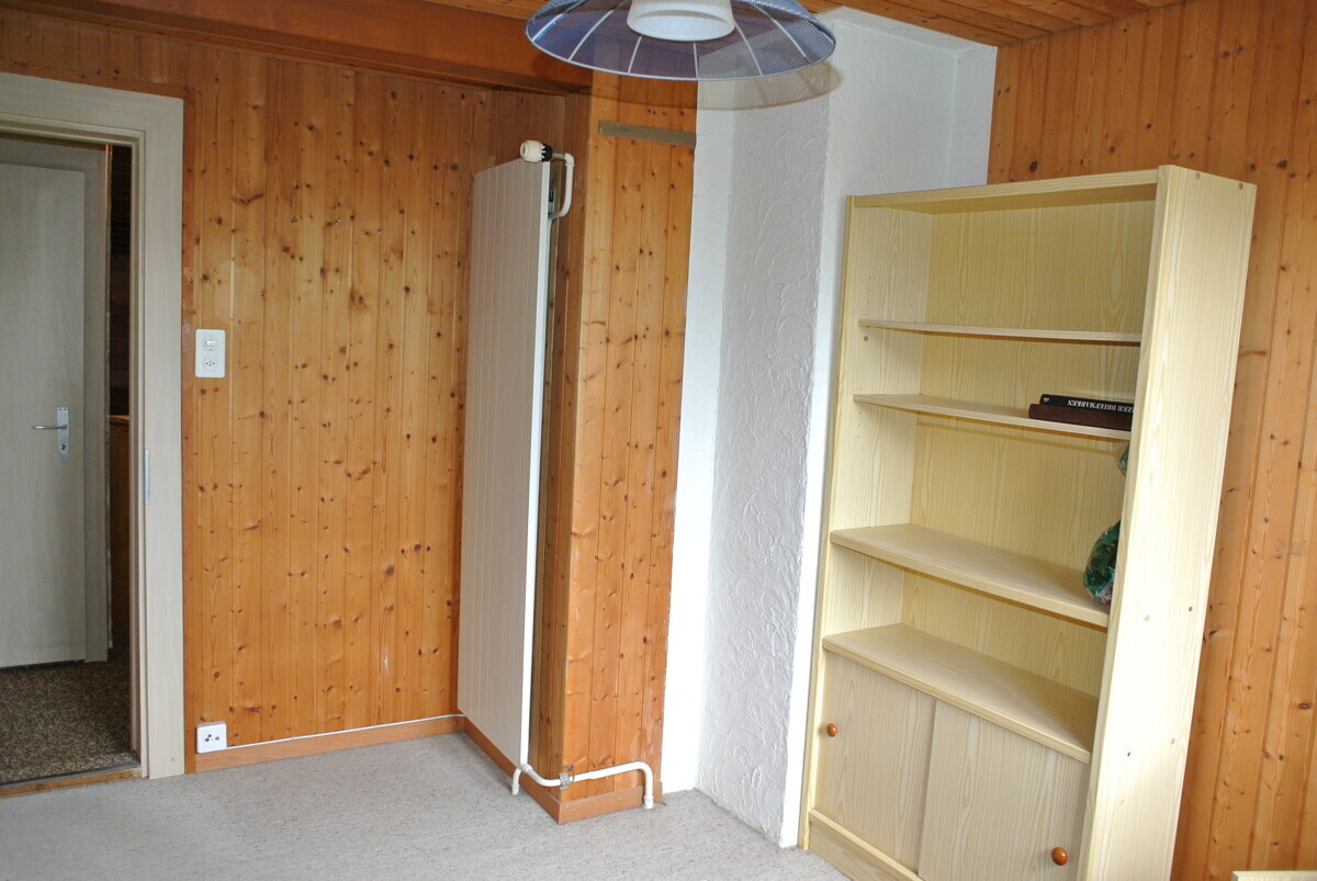 Holzvertäfelter Raum mit Heizkörper und Regal