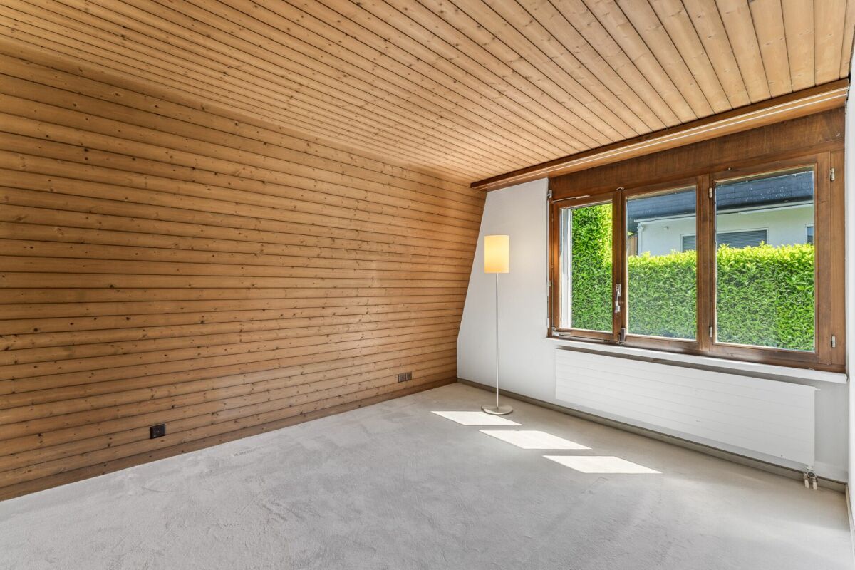 Heller leerer Raum mit Holzverkleidung und großem Fenster
