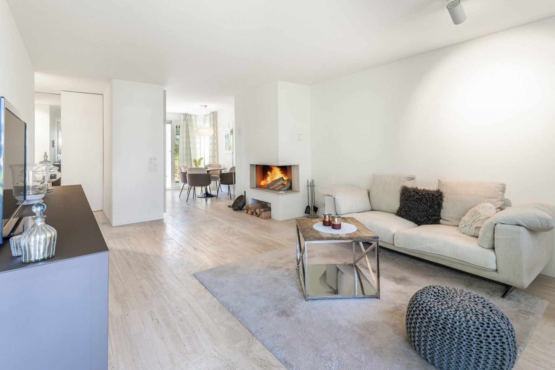 Heller Wohnraum mit Kamin und Essbereich im Hintergrund
