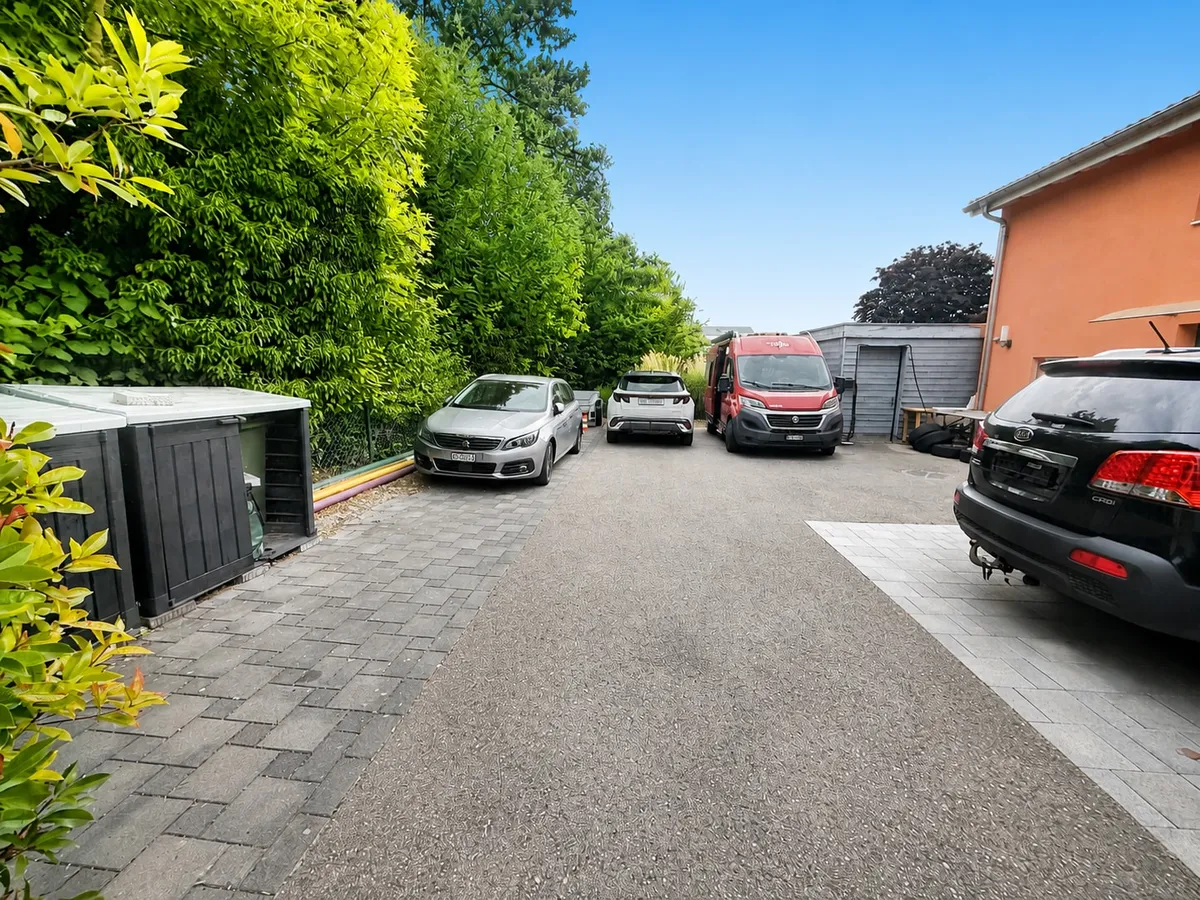 Außenbereich mit Zufahrt und geparkten Fahrzeugen